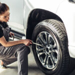 خانم درحال بازکردن پیچ چرخ یک ماشین شاسی بلند