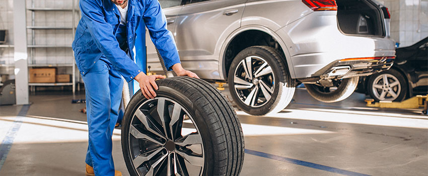 مرد درحال هل دادن لاستیک ماشین با رینگ نقره ای رنگ