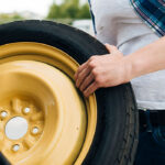 مرد درحال درآوردن لاستیک ژاپاس ماشین با زینگ زرد