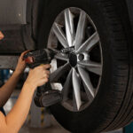 یک خانم در حال بازکردن پیچ های چرخ ماشین