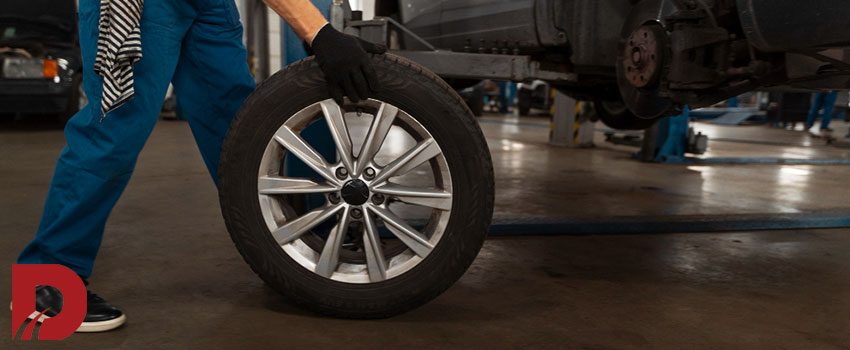 مکانیک در حال حمل لاستیک ماشین