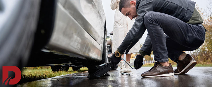 مکانیک در حال نصب جک زیر ماشین