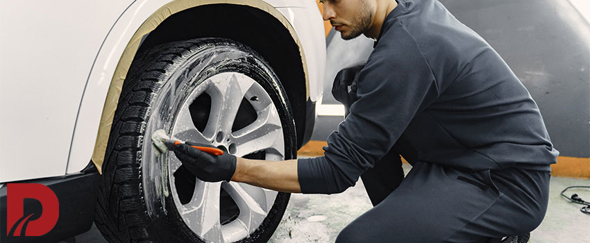 مکانیک در حال کف زدن به چرخ ماشین