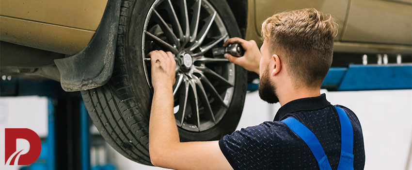 مکانیک در حال بررسی چرخ ماشین