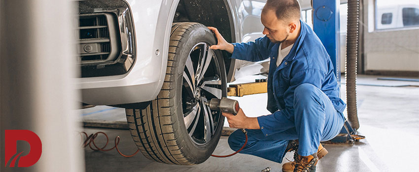 مکانیک در حال محکم کردن مهره های چرخ ماشین