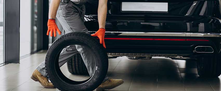 مکانیک در حال هل دادن لاستیک نو پشت یک ماشین