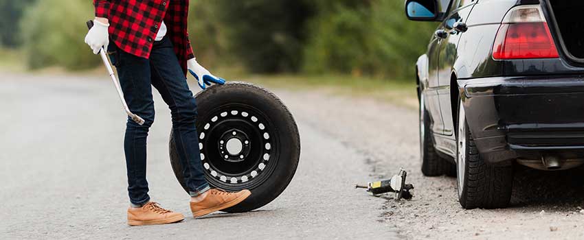 مرد در حال تعویض لاستیک در کنار جاده