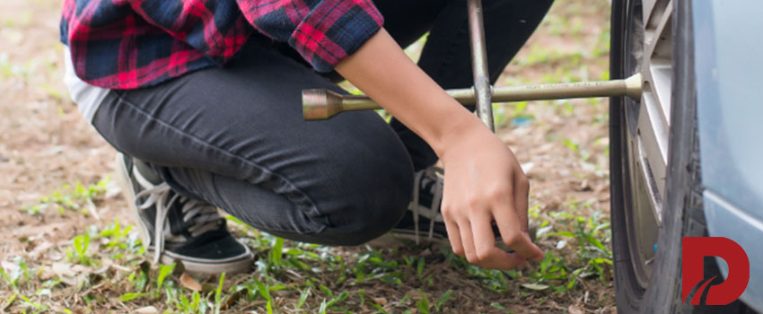 مرد در حال محکم کردن پیچ چرخ ماشین