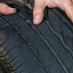 نمای نزدیک از یک لاستیک و دستان شخصی که آنرا نگه داشته است