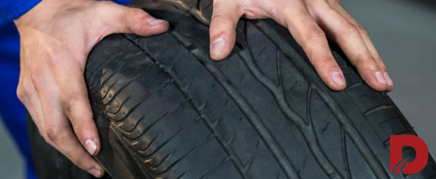 نمای نزدیک از یک لاستیک و دستان شخصی که آنرا نگه داشته است