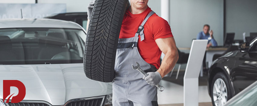 مکانیک در حال حمل یک حلقه لاستیک روی شانه اش