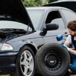 مکانیک در حال تعویض لاستیک ماشین در کنار جاده