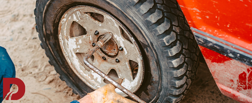 مکانیک در حال محکم کردن مهره های چرخ ماشین با آچار