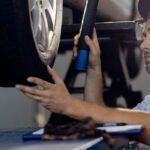 مکانیک در حال بررسی لاستیک ماشین با چراغ قوه