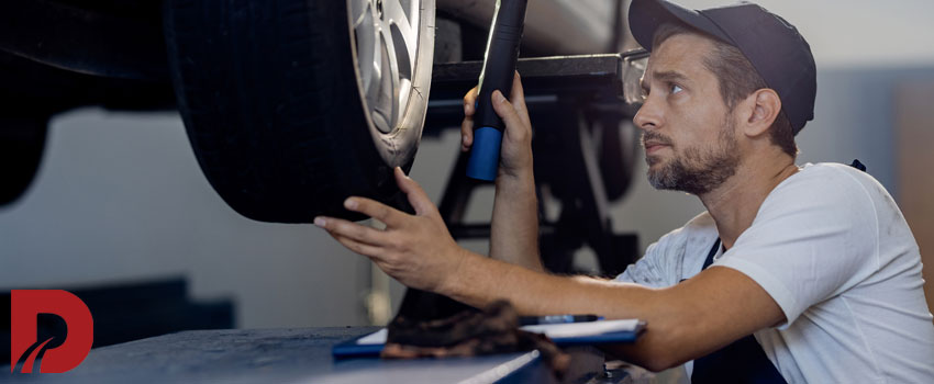 مکانیک در حال بررسی لاستیک ماشین با چراغ قوه