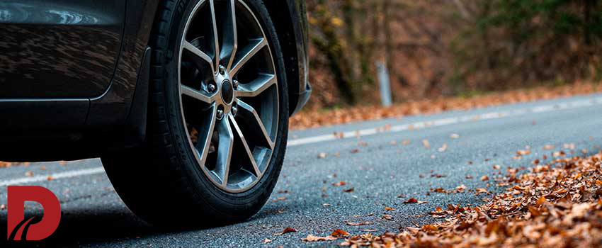 نمای نزدیک از لاستیک ماشین در کنار جاده پاییزی