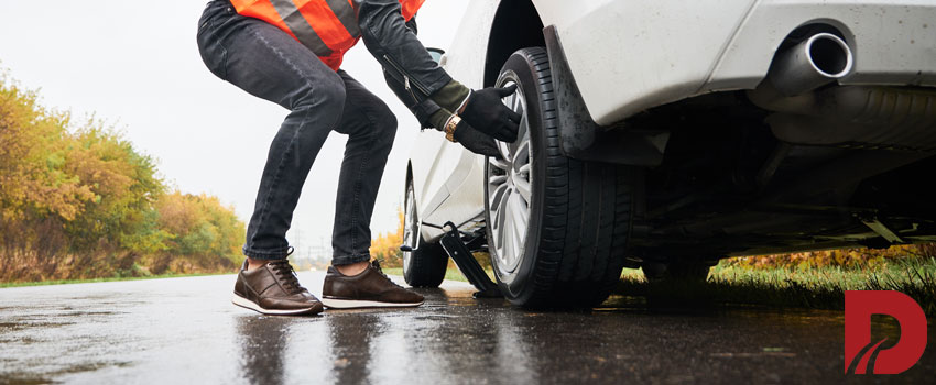 مکانیک در حال تعویض لاستیک ماشین کنار جاده