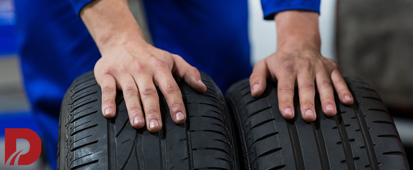 تعمیرکار درحال حمل دو لاستیک متفاوت درکنار هم