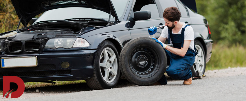 مکانیک در حال تعویض لاستیک ماشین در کنار جاده