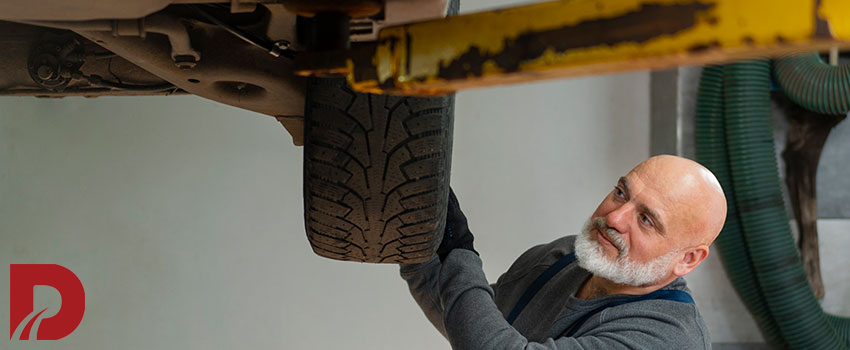 مرد مکانیک درحال بررسی لاستیک در تعمیرگاه